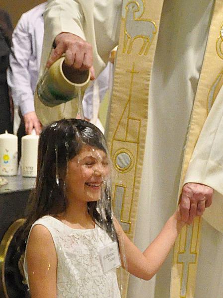 Archbishop Etienne Baptizes a young girl by pouring holy water over her head
